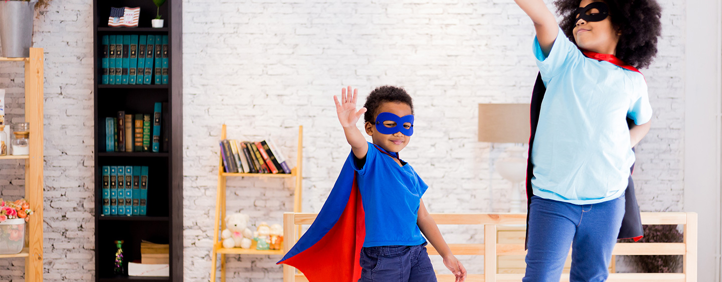 Two kids dressed up as superheroes and playing.