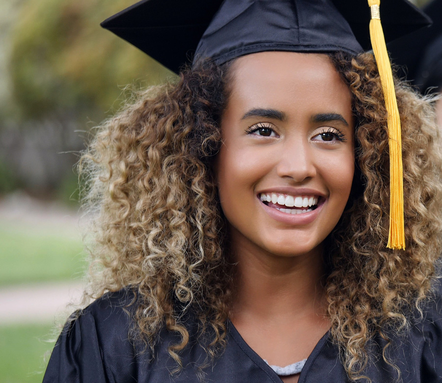 A woman smiles in a graduation cap and robe