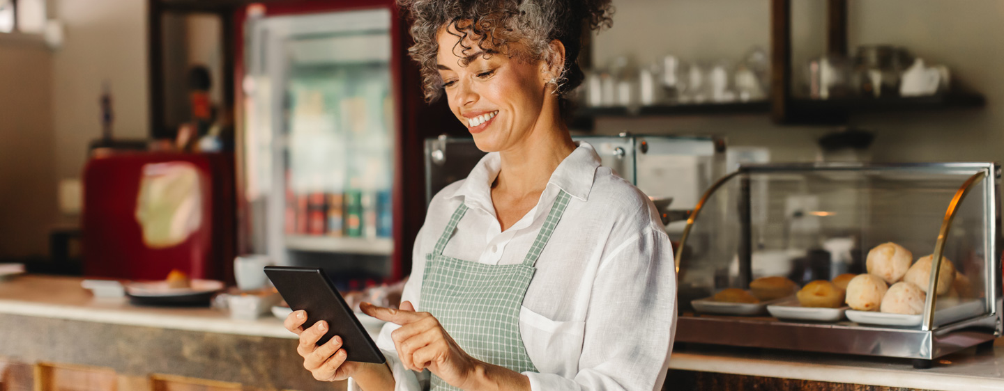 Image of a woman who owns a bakery checking on her business via tablet.