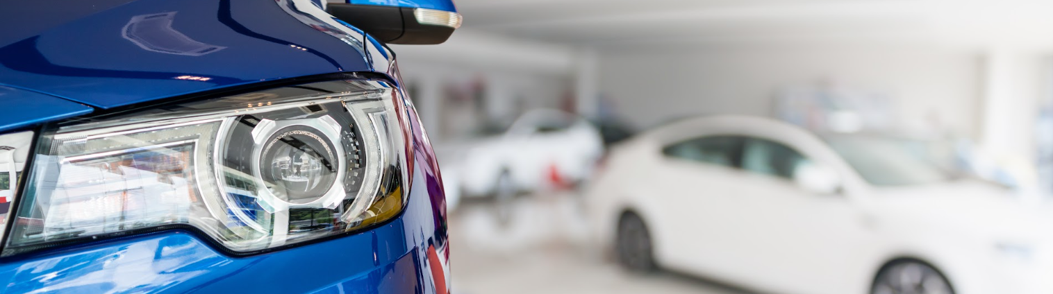 Close-up of a blue car in a showroom for tips to lower car payment without refinancing