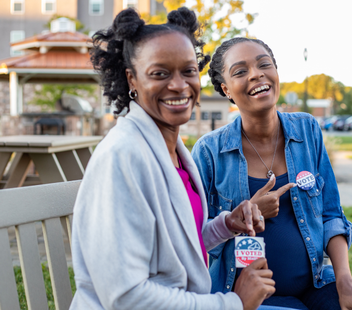 Two individuals showing "I Voted" stickers.