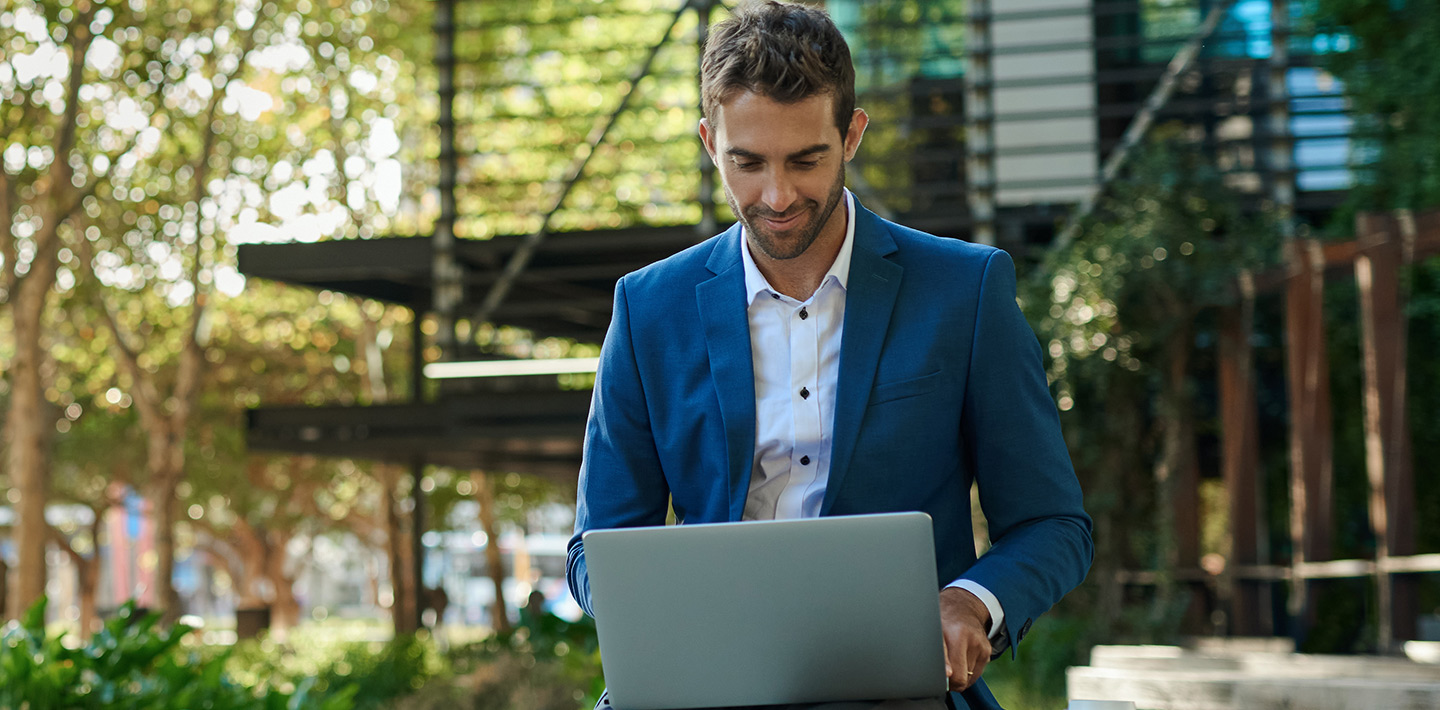 Man in a suit on his laptop outside.