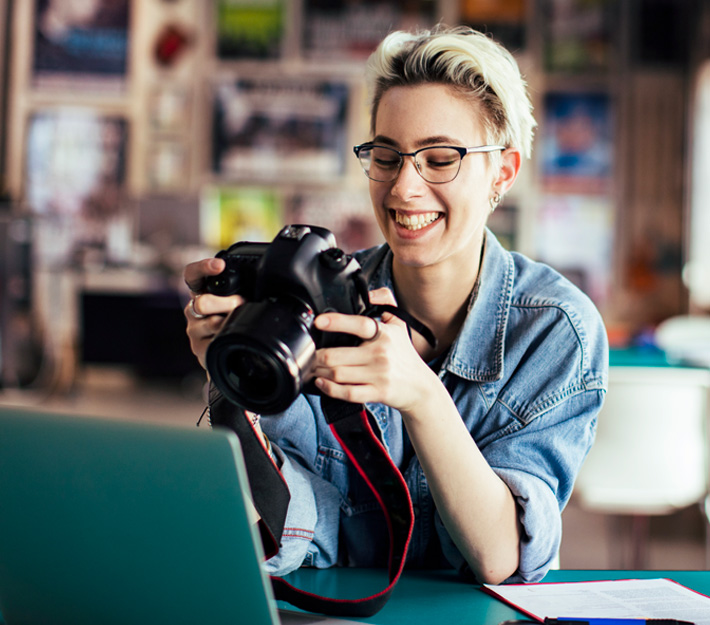 Woman looks at a camera in her hands in an art shop.