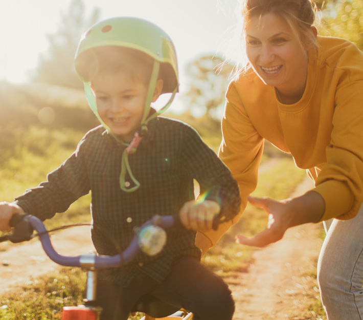 Image of a mom teaching her young son to ride a bike.