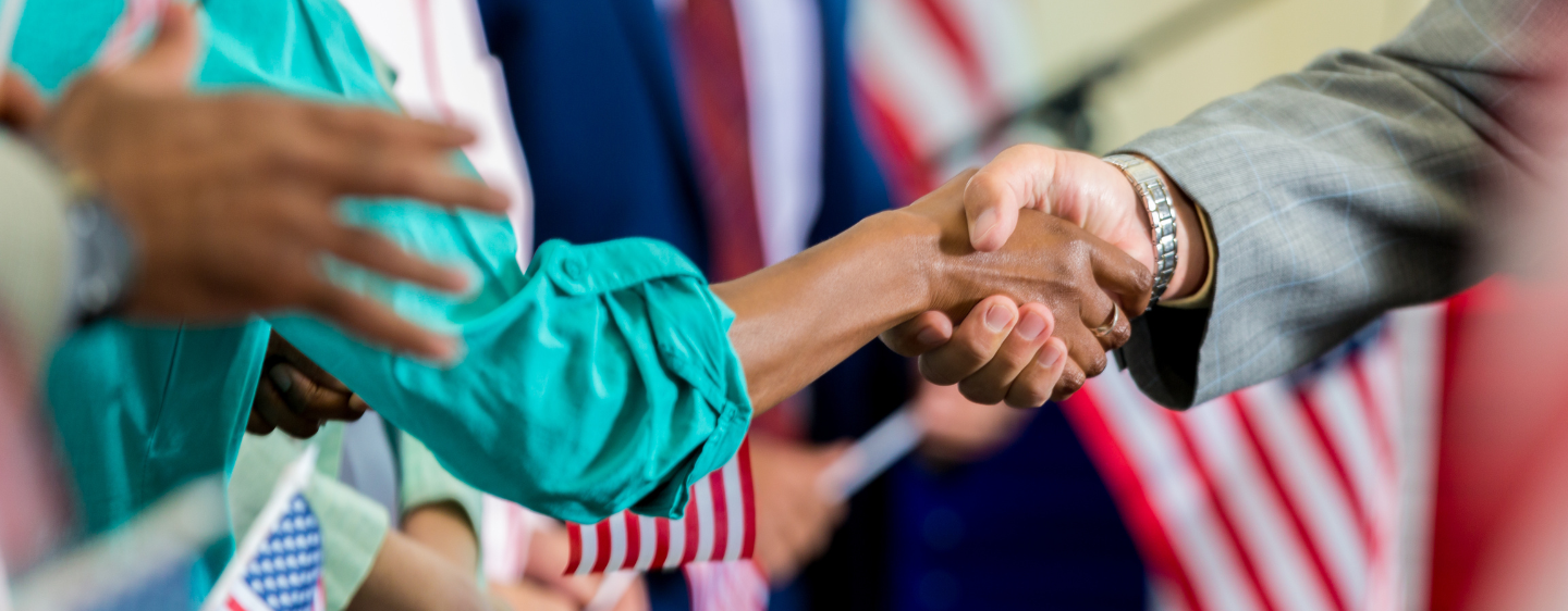 Photo depicting hands shaking and American flags. 