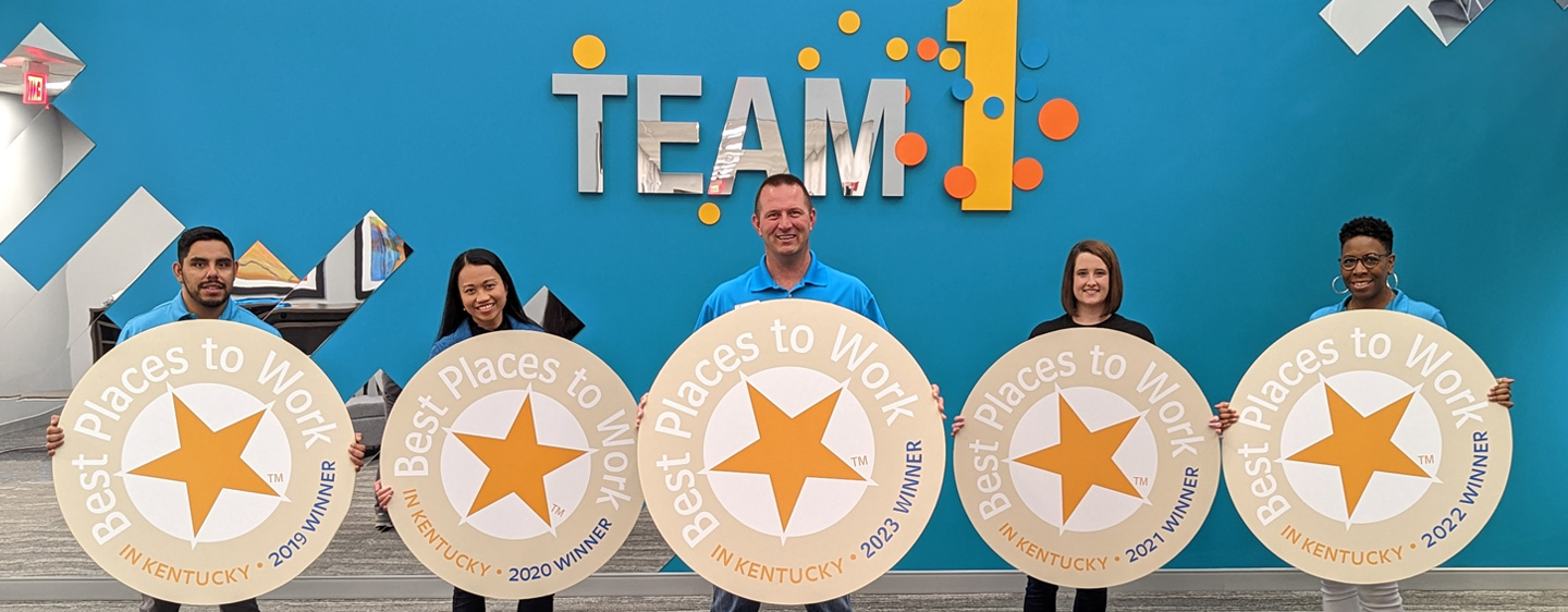 An image of Team 1 workers smiling and holding Best Places to Work cutouts