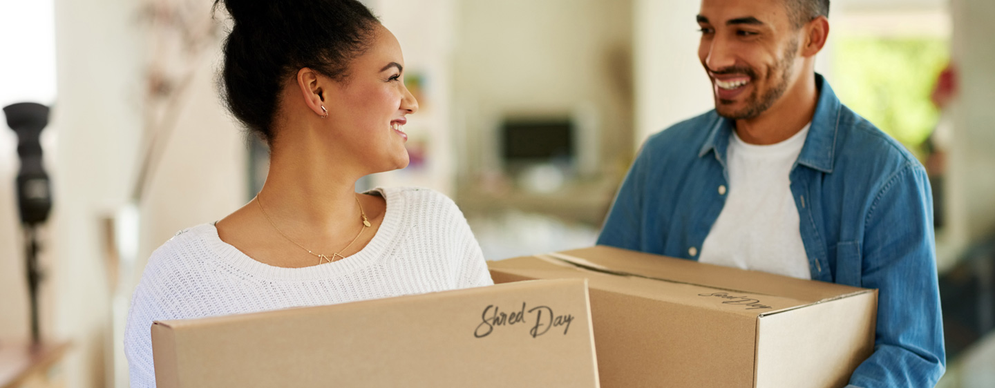 Woman and man hold boxes to take to shred day.