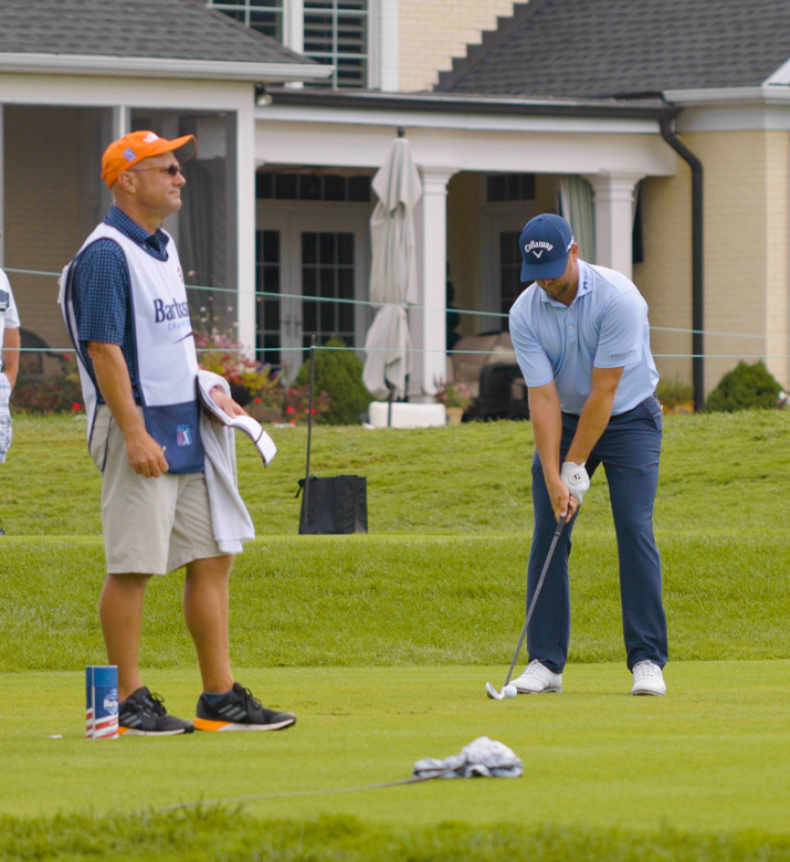 Image of a man golfing at the Barbasol tournament while a scorekeeper stands nearby