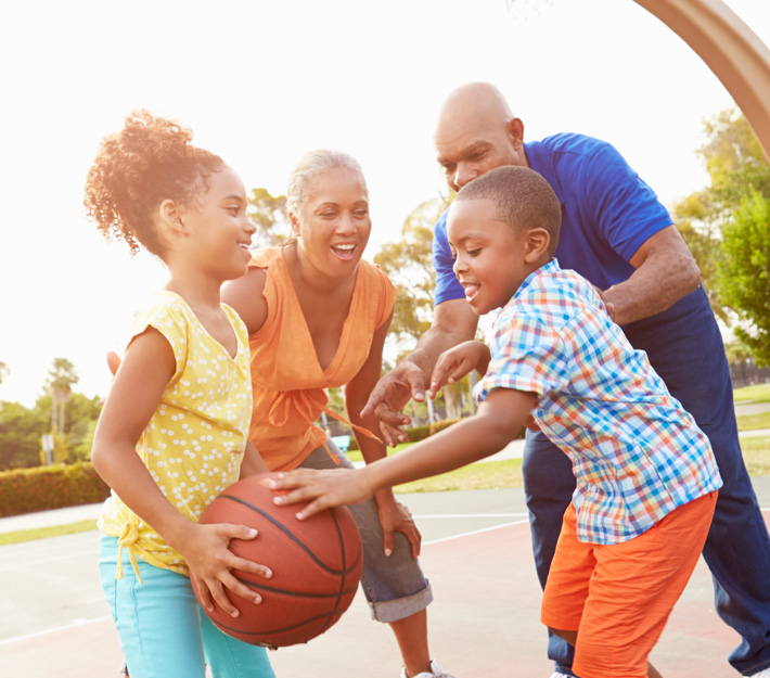 Young girl holding basketball while playing with her brother and grandparents.