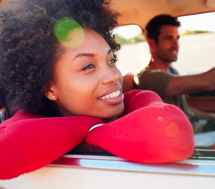 A man and a woman smile in a car.