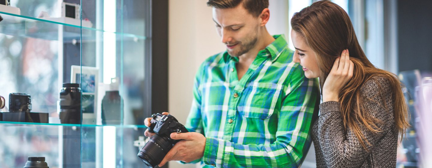 Couple look at a camera they're planning to buy in a store.