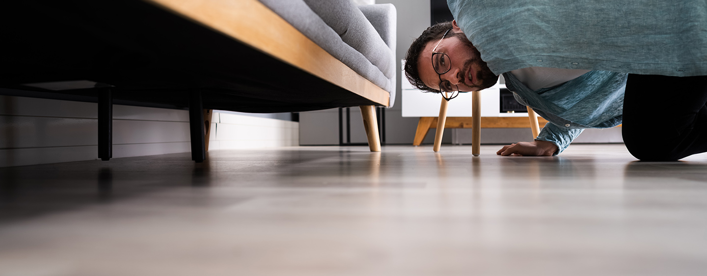 Man looking for something under couch.