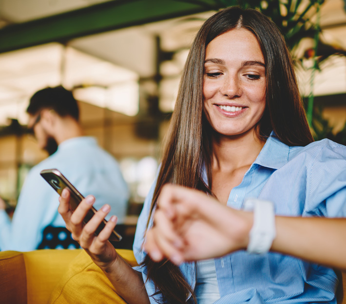 Image of a woman in public using her phone and checking her watch