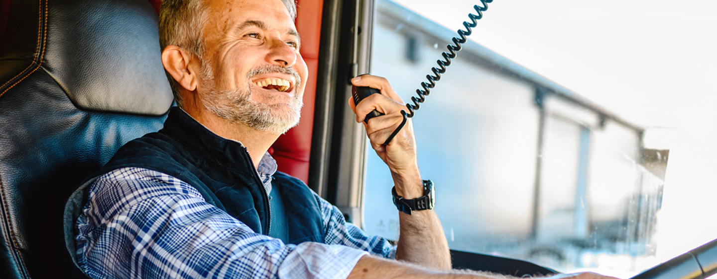 A man smiles while driving a truck.