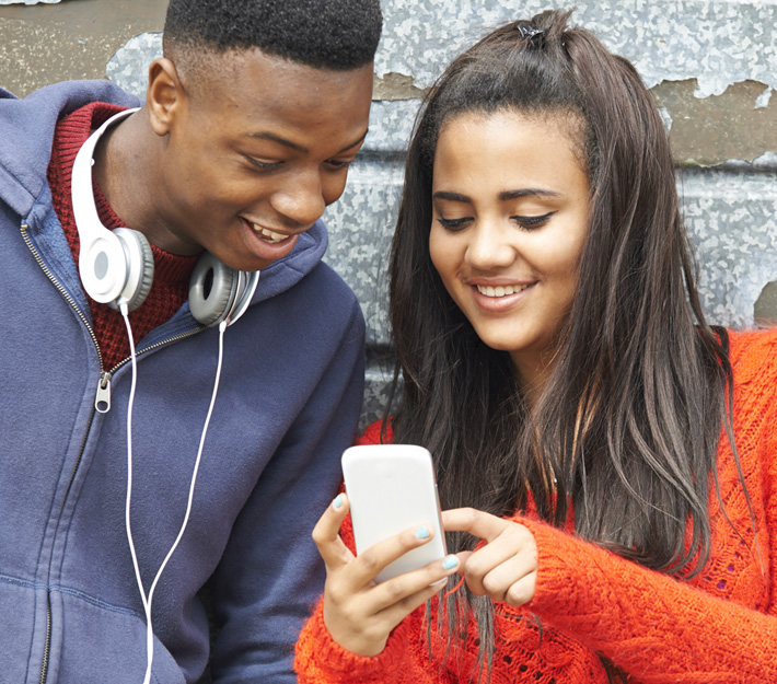 A girl showing her friend something on her phone.