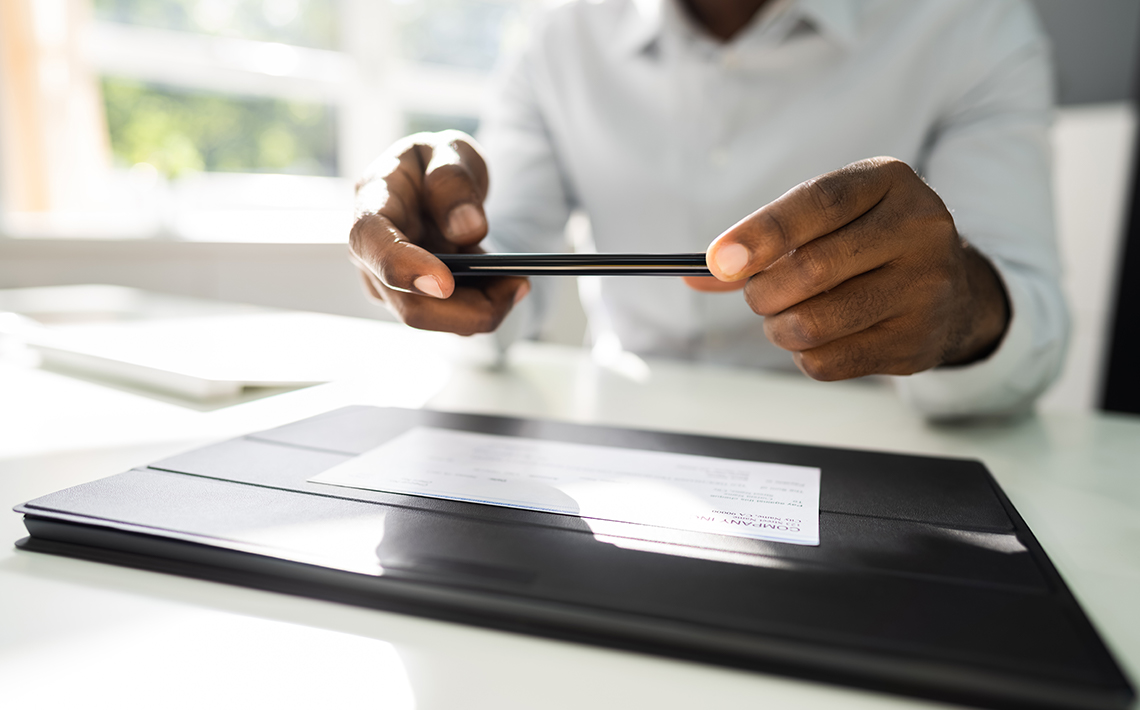 Man scanning a check on a dark surface to make a mobile deposit.