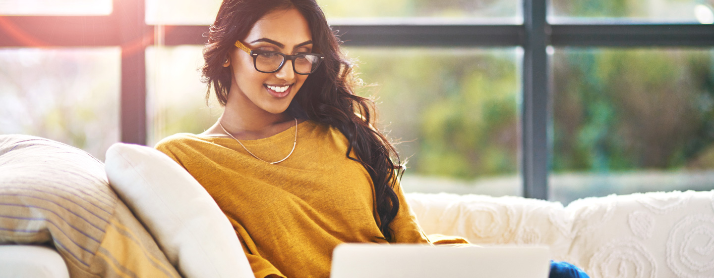 Woman uses a laptop on a couch.