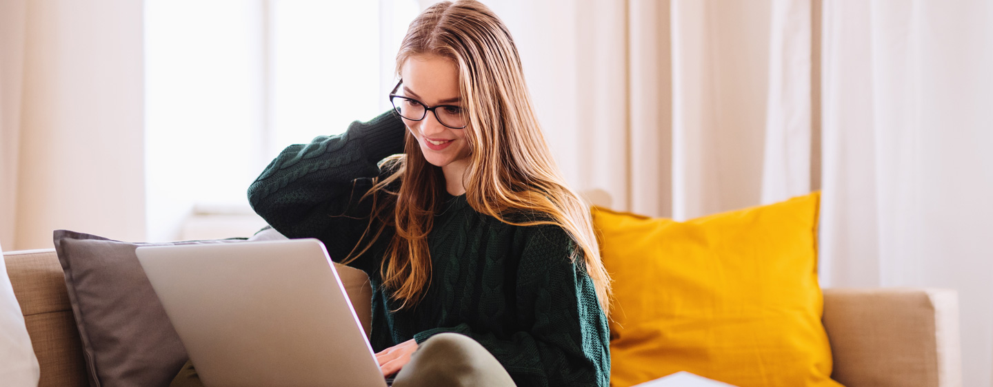 A young woman on a couch uses a laptop.