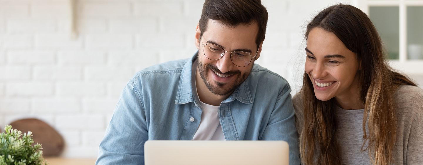 Couple looking at computer screen and smiling.