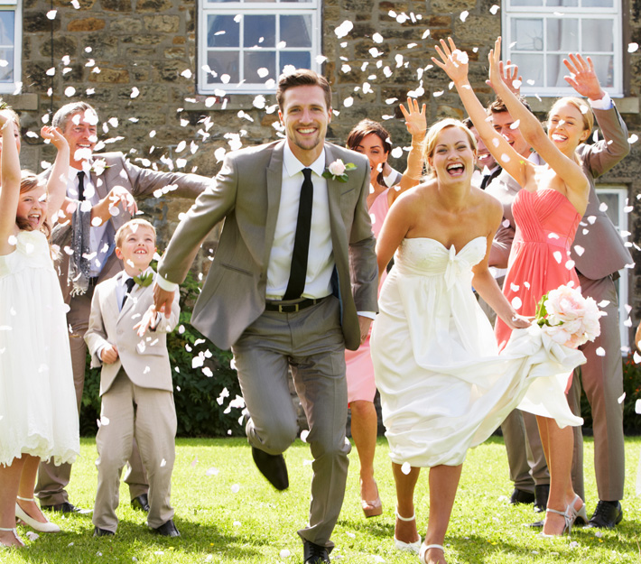 Just married husband and wife run through a shower of flower petals.