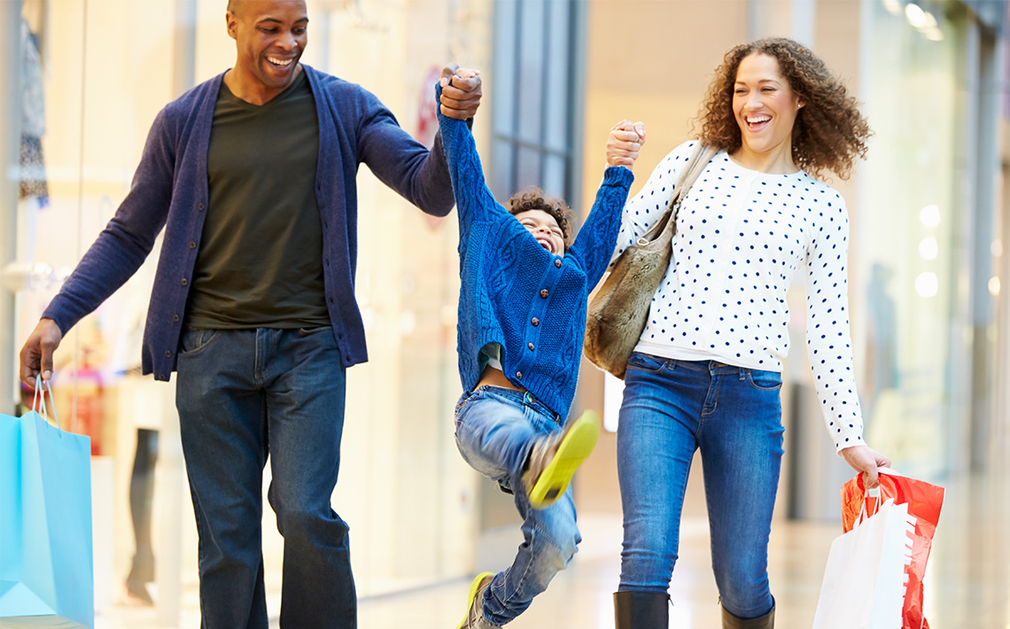 Family swinging their child while shopping.