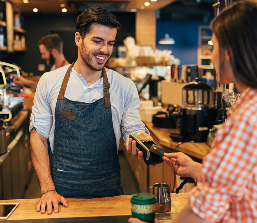 Image of a woman using tap to pay with her MY Card at a coffee shop