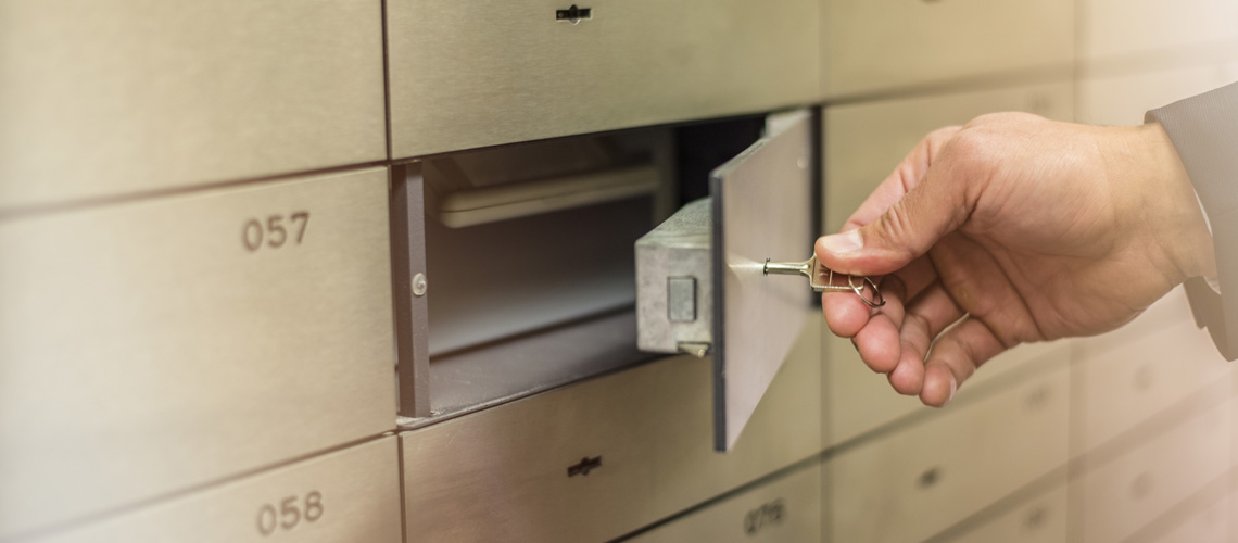 Image of a hand opening a lock on a Safe Deposit Box