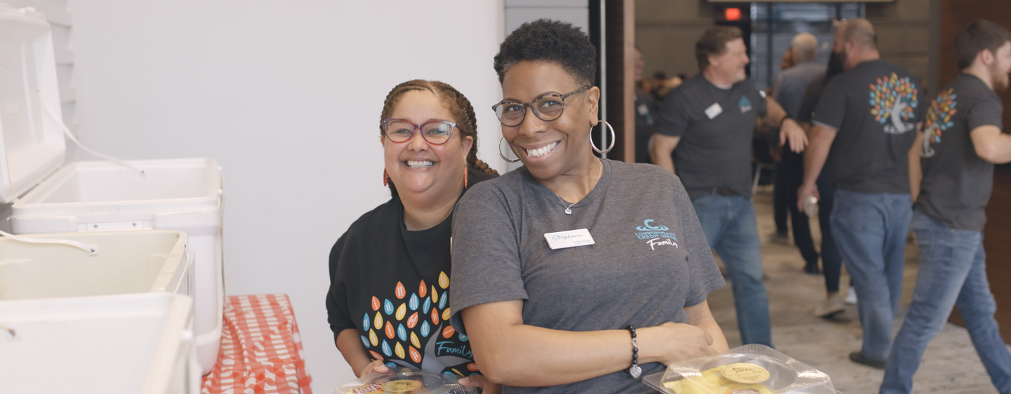 Two CCU team members smile together at an event