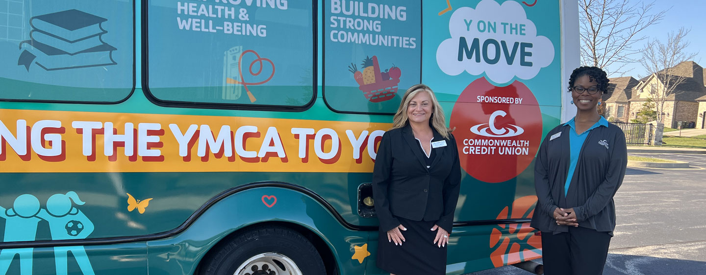 CCU team members stand by a YMCA bus sponsored by CCU