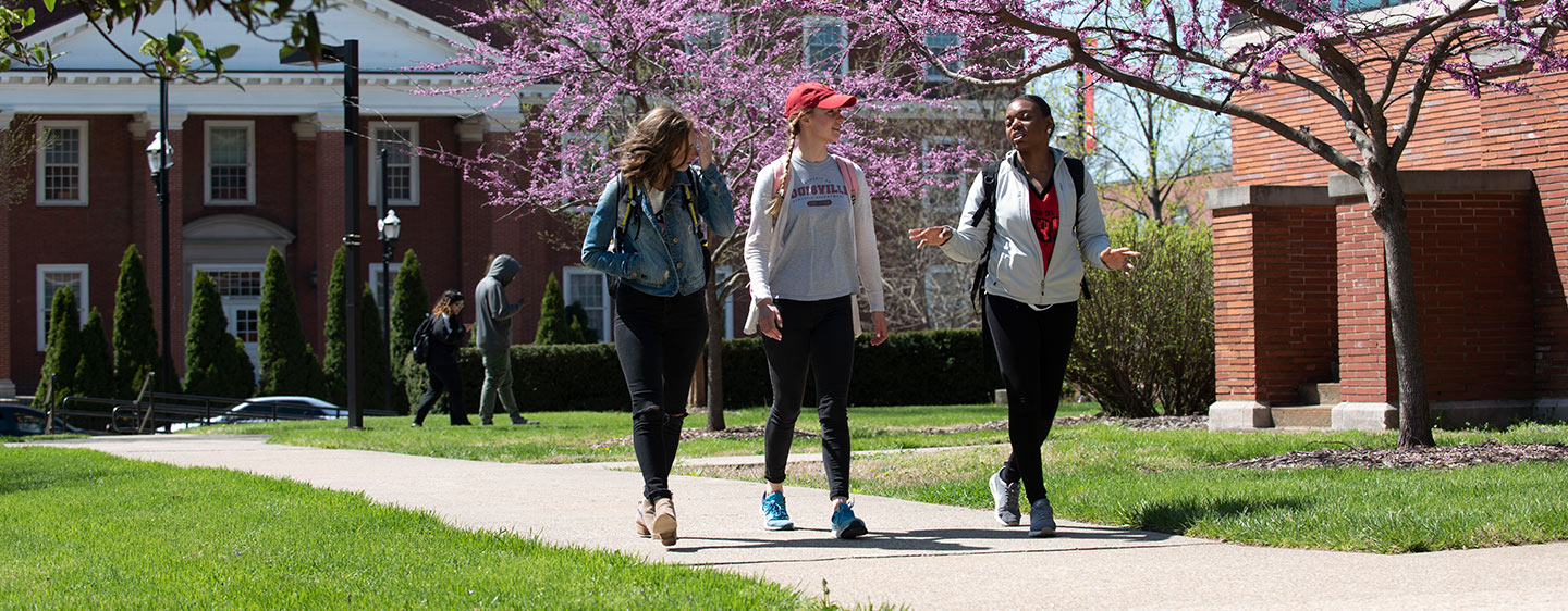 Three students walking across campus at the University of Louisville.