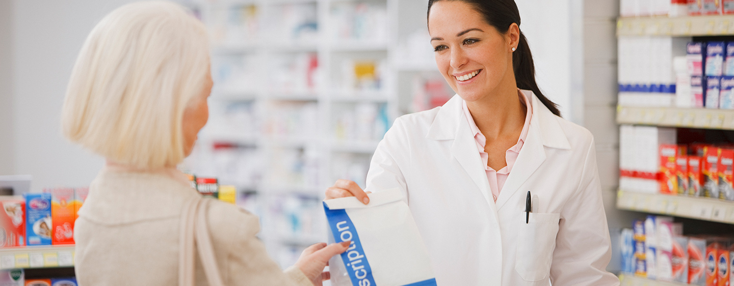 Pharmacist handing bag of prescriptions to customer.