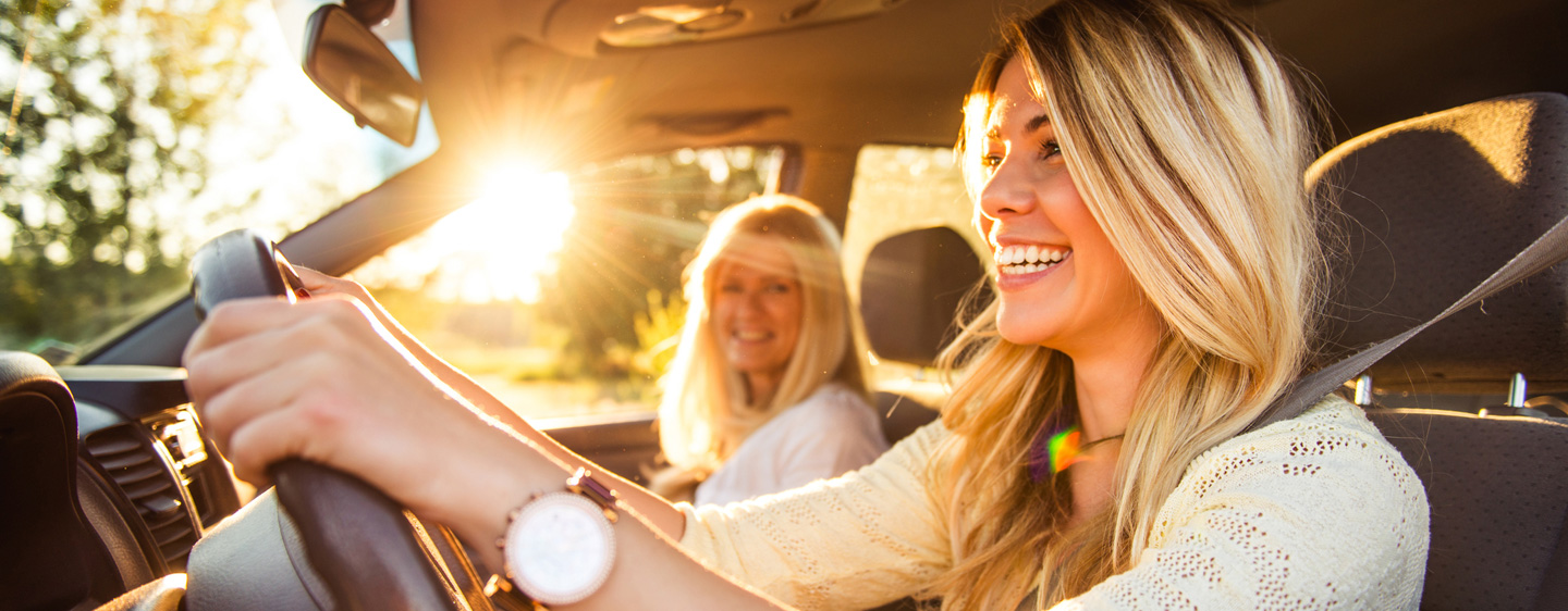 A woman smiles behind the steering wheel of a vehicle.