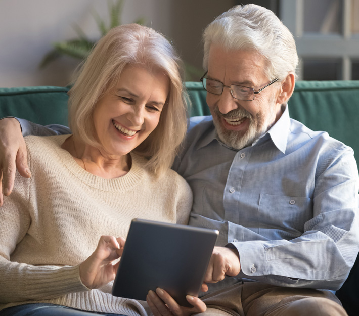 Smiling older couple looking at a tablet.
