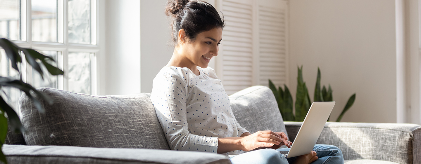 Female student on the couch using a laptop.