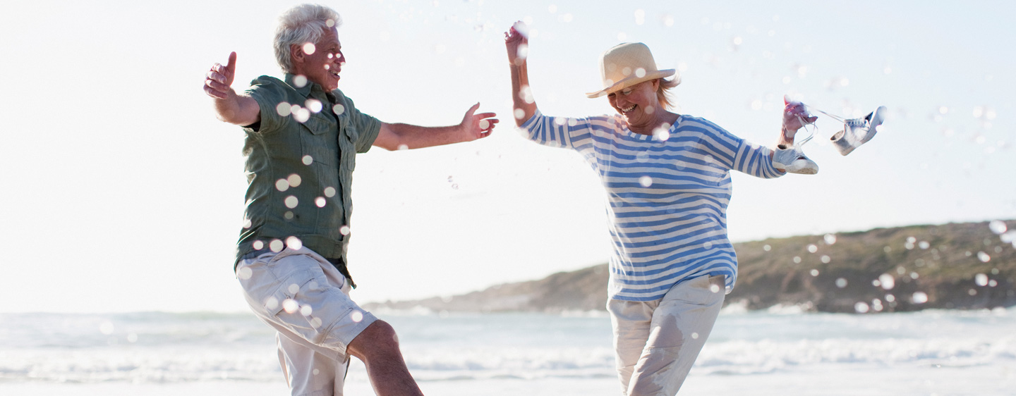 Retired couple play in ocean waves.