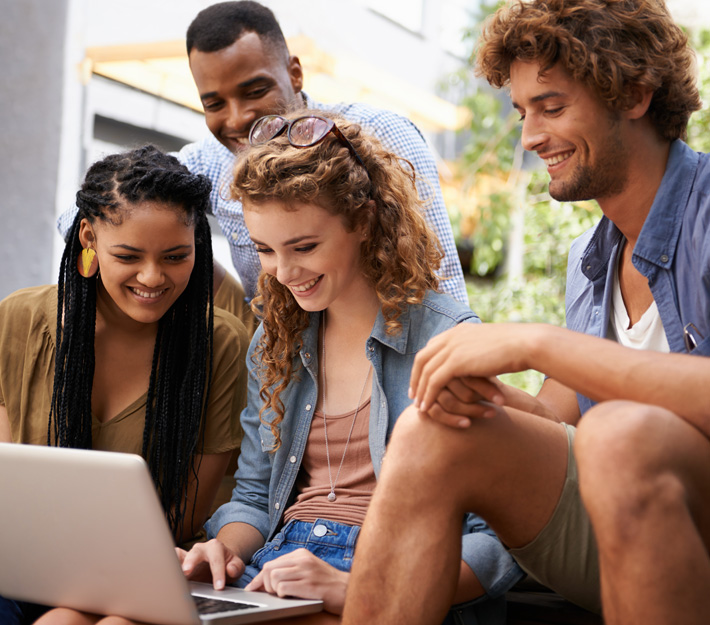 A group of students use a laptop together.