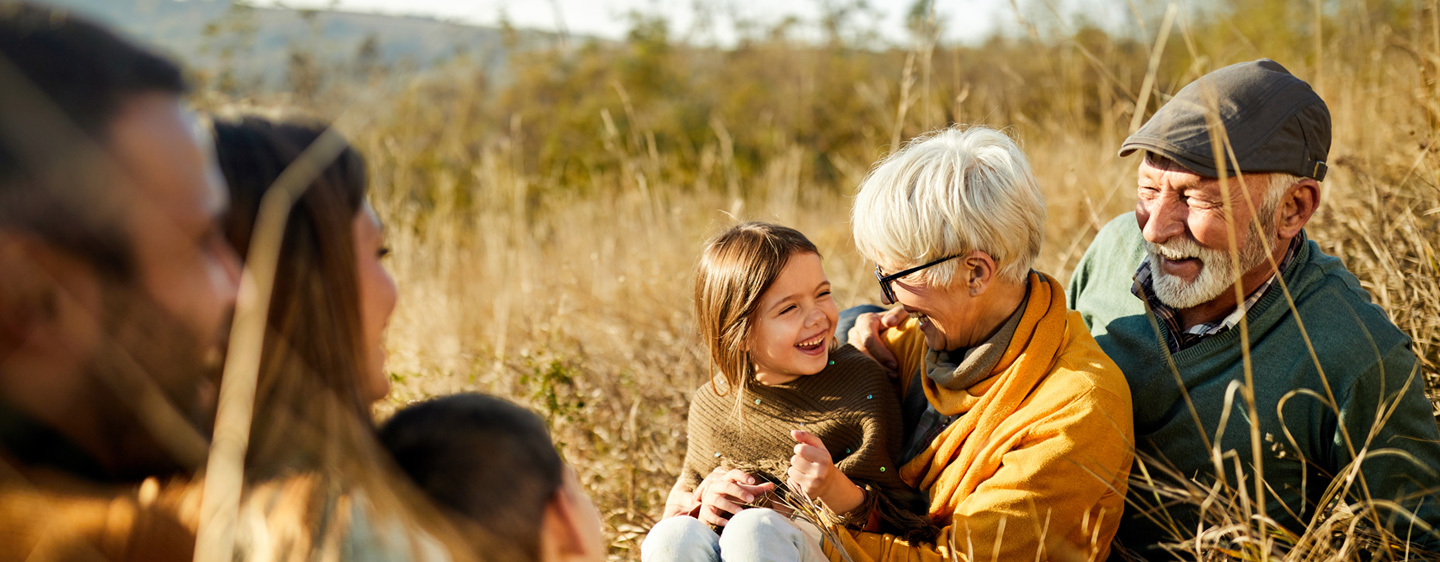 Image of grandparents smiling with a grandchild in a field