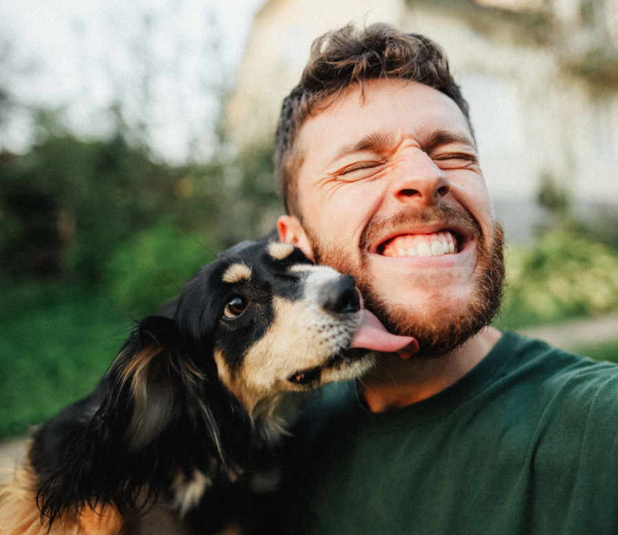 Man smiles as dog licks his face