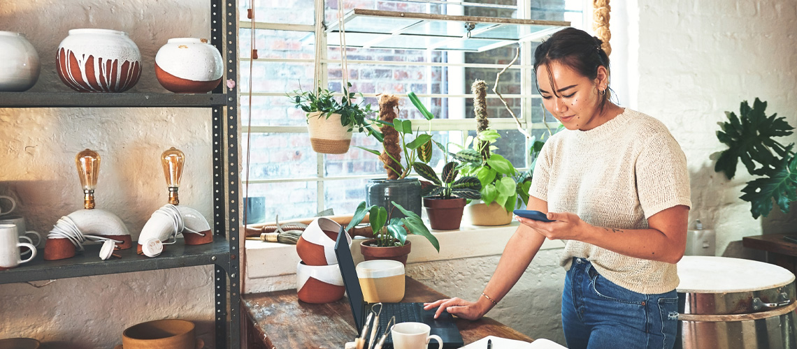 Woman working at her business smiles at her phone.