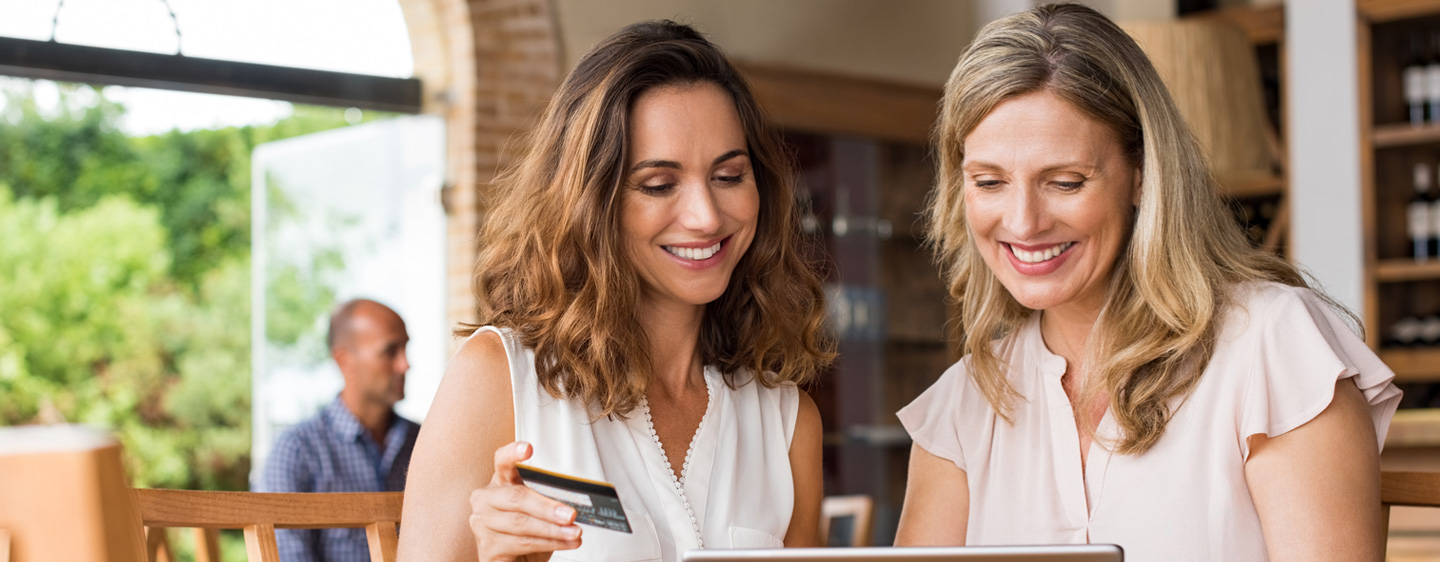 Woman helping another woman to purchase something with a credit card.