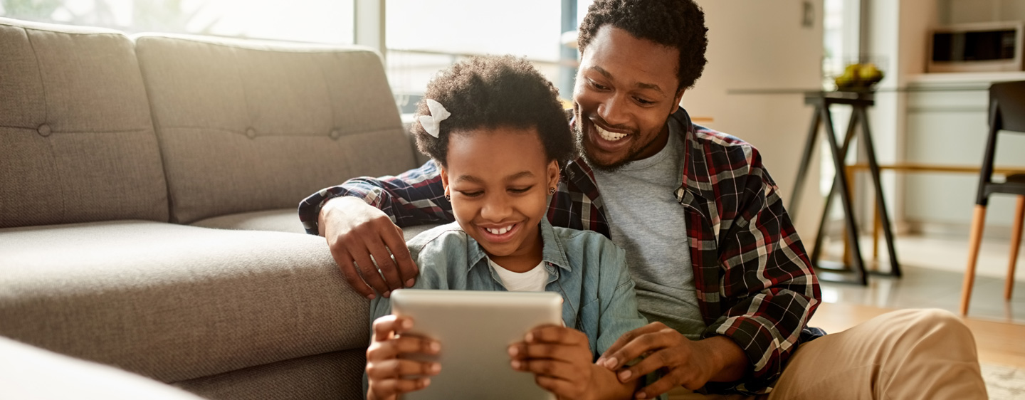 Man and his daughter look at a tablet together.