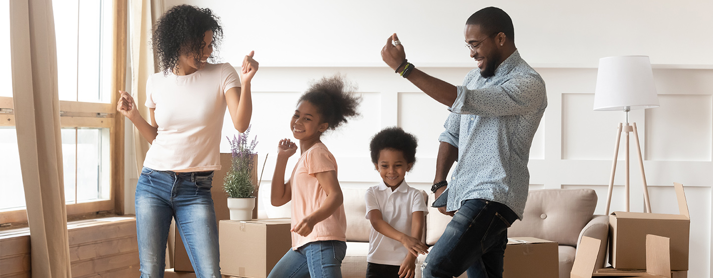 Mom, dad, and two kids dancing in the living room.