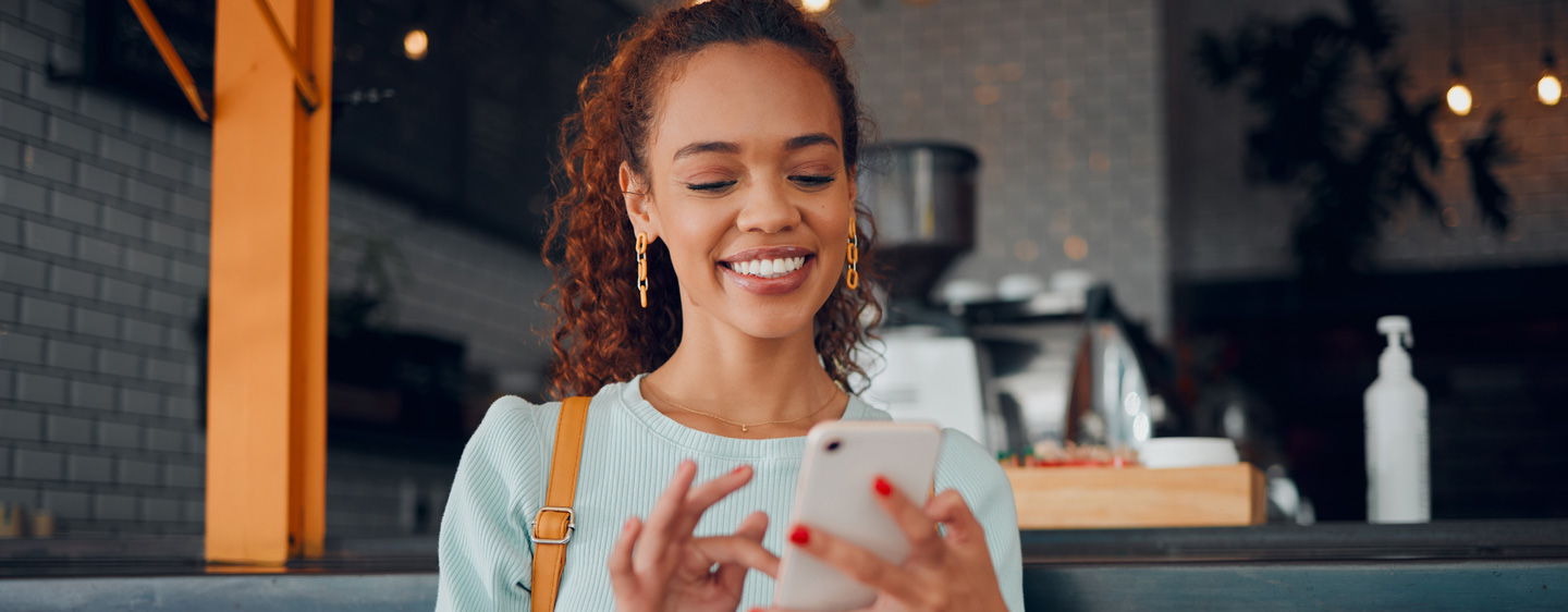 Woman smiles at her cell phone in a coffee shop