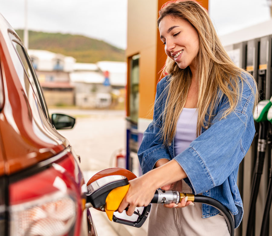 Woman putting gas in her car at a gas station.