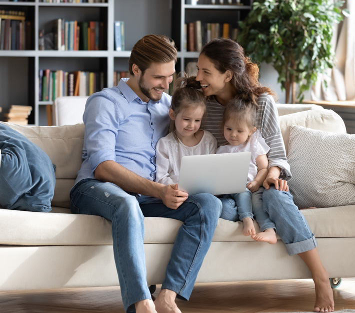 Mom, dad, and two daughter watching tablet on the couch.