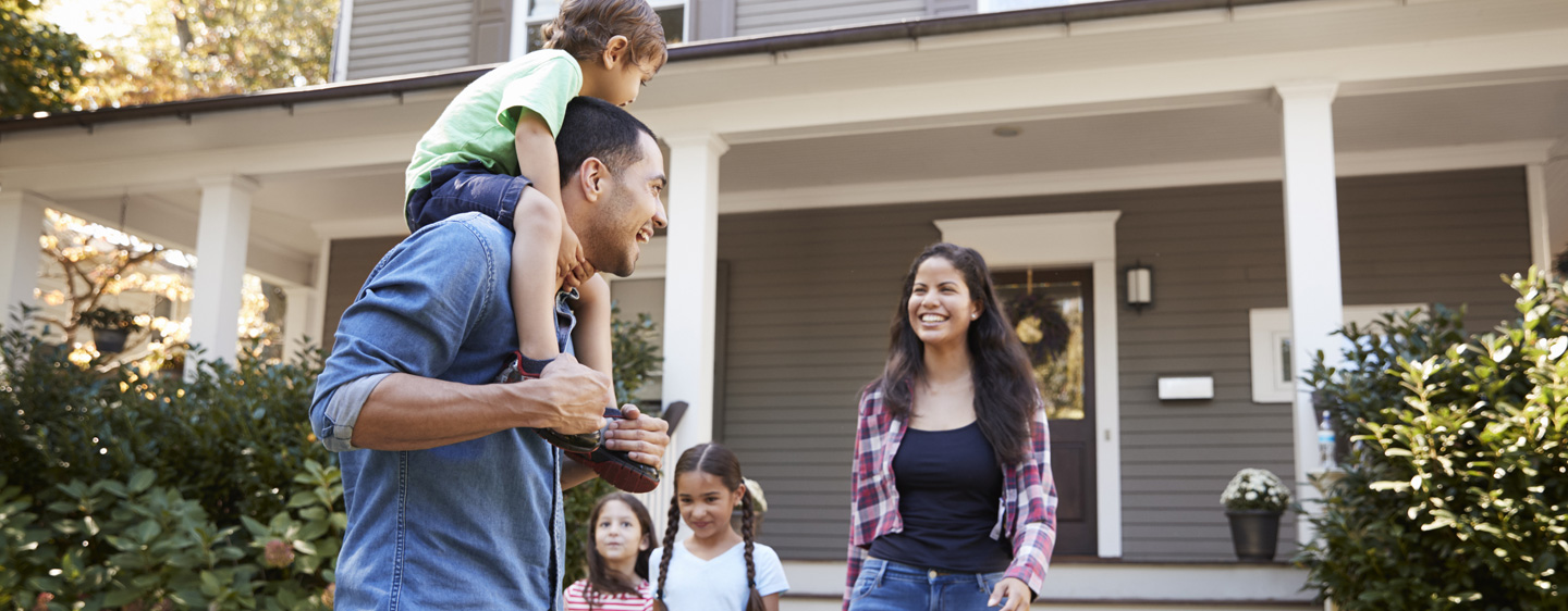 Family smiling together outside of their house