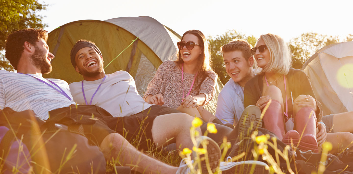 Group sits together outside of a campsite.