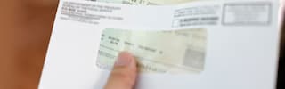A hand holding an official United States Treasury check inside its envelope, representing a strategic tax refund debt payoff plan.
