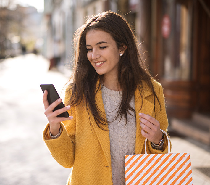 Woman carrying shopping bag looking at phone