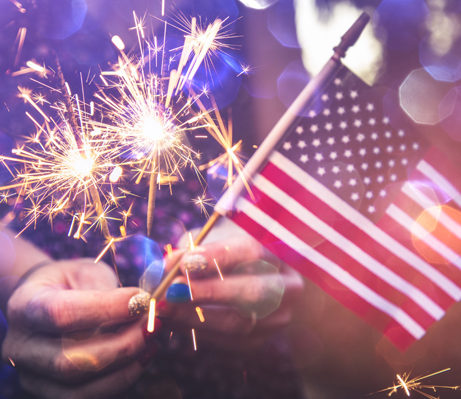 Image of someone holding a small American flag and a couple of sparklers for July 4th